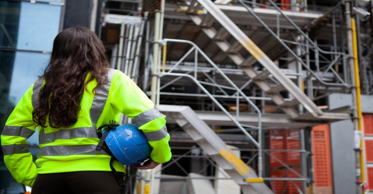 elev fotad bakifrån framför byggställningar.