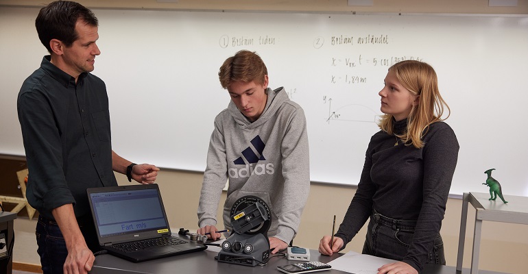 Lärare som visar två elever hur man gör fartberäkning.