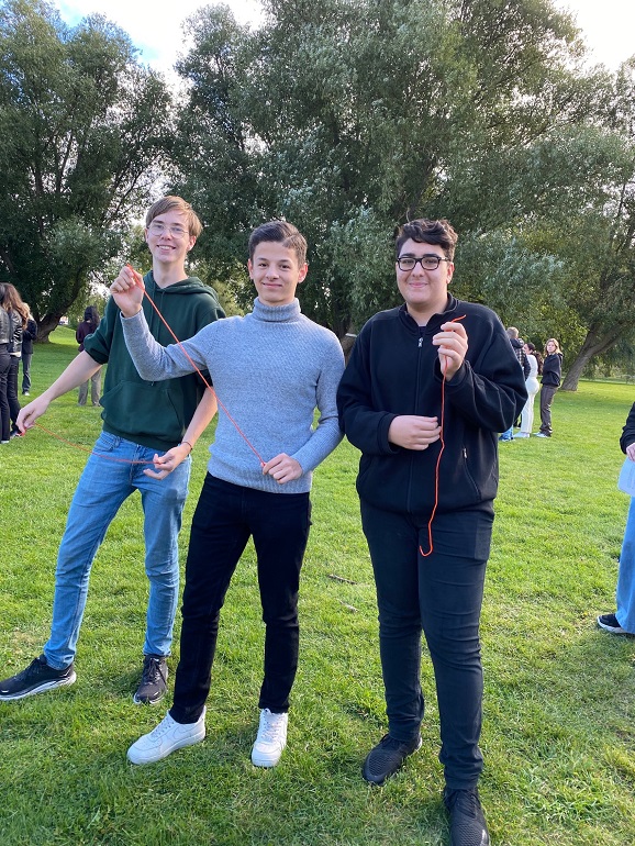 tre elever som tittar in i kameran och håller upp ett snöre.