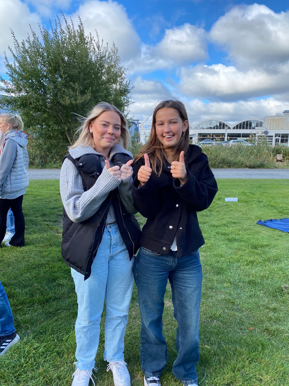 två elever som tittar in i kameran och gör tummen upp.